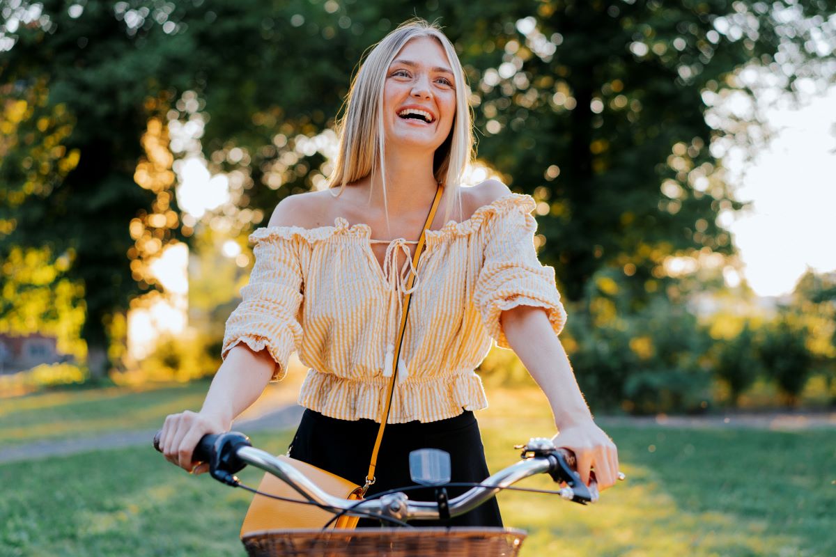 En ung kvinna som ler stort samtidigt som hon håller i en cykel