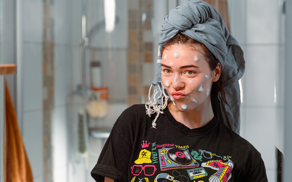 Ung kvinna står framför spegel med pluppar av L300 cleansing mousse i ansiktet