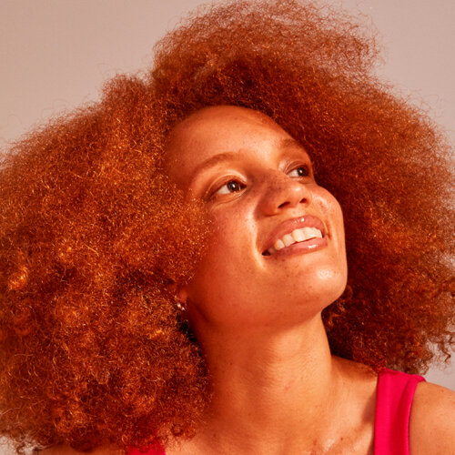 Kvinna med orange hår tittar snett uppåt